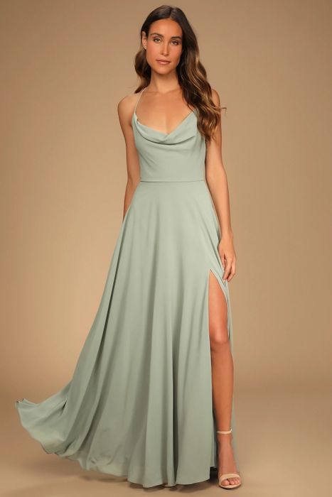 A model is dressed in a sage green dress, complemented by nude shoes.