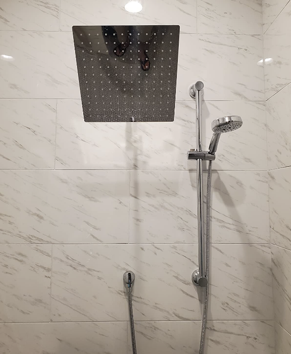 Reviewer's showerhead installed in a marble shower.