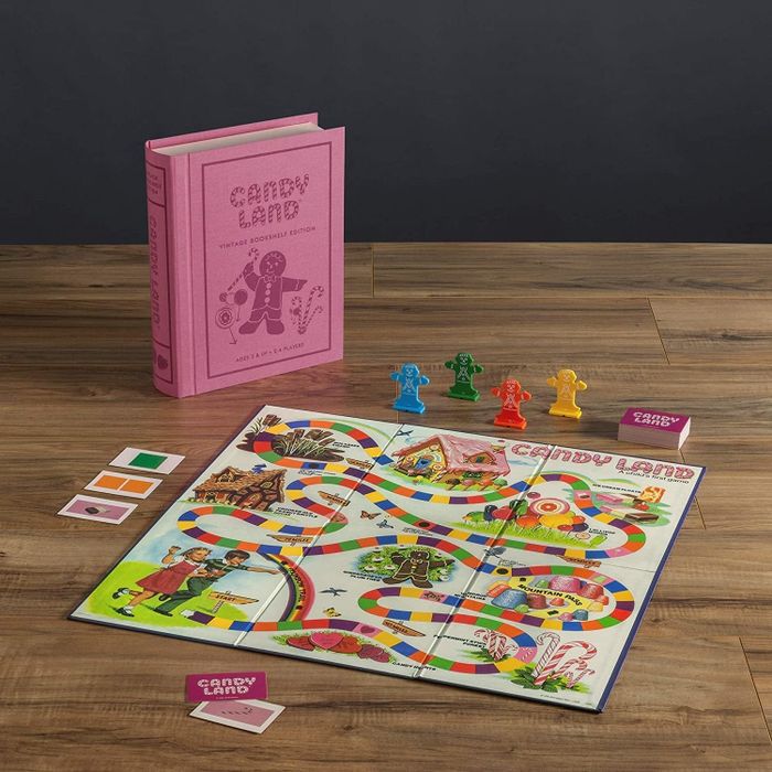 A box containing a Candy Land game next to a pink book box.