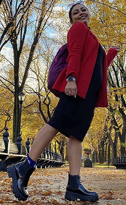 Reviewer wearing the black boots paired with a black dress and a red jacket