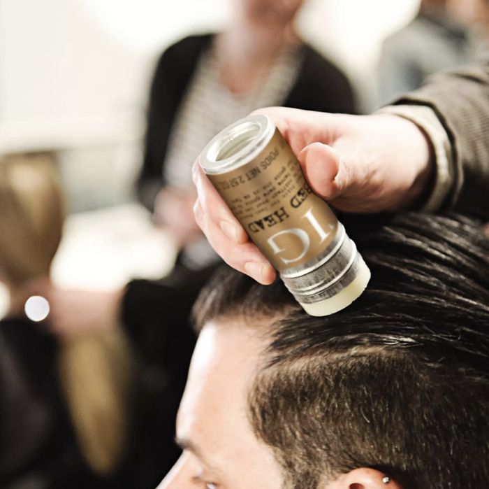 a person applying a wax stick to a model's hair