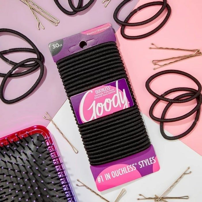 A pack of black ponytail holders surrounded by pink and purple packaging and other hair tools