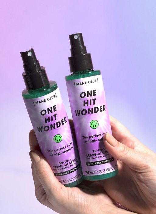 Hands holding two bottles of leave-in conditioner spray