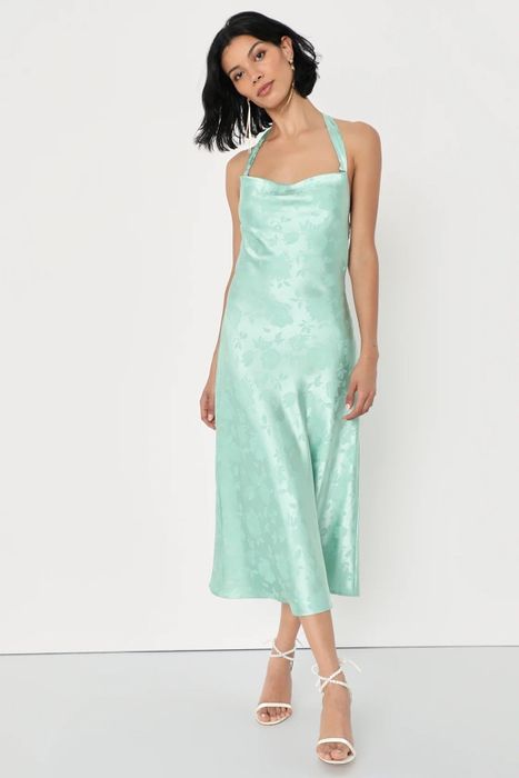 A model wearing a green dress with white shoes.