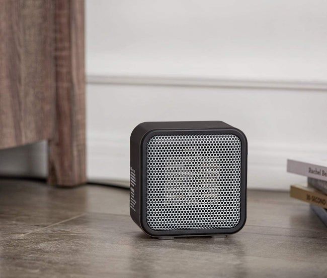 The black mini heater resting on the floor.