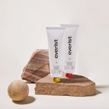 Two bottles of hair concentrates placed on a rock, showcasing their compact design.