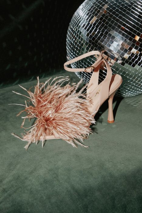 A pair of pink heels with feather accents.