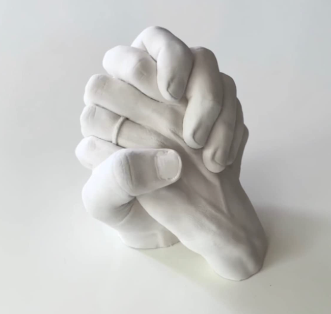 Finished clay hand sculpture holding an item, created by reviewers.