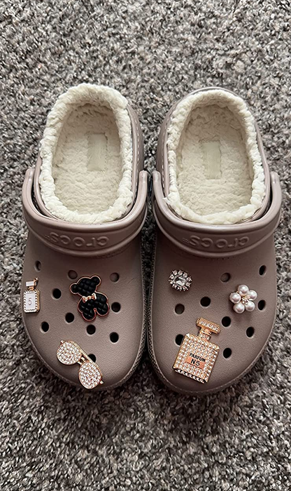A reviewer proudly displays their pair of fuzzy brown Crocs.