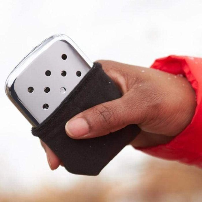 A model showcasing the silver hand warmer in their hand.