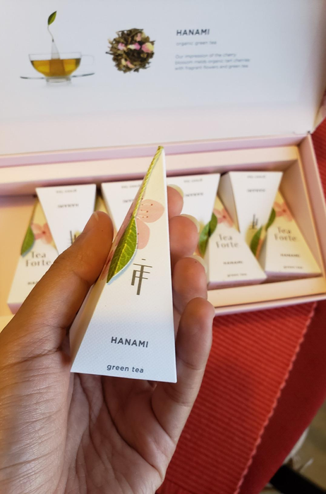 A reviewer holding up a green tea bag in front of the camera.