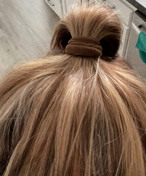 reviewer's hair styled with a brown hair tie