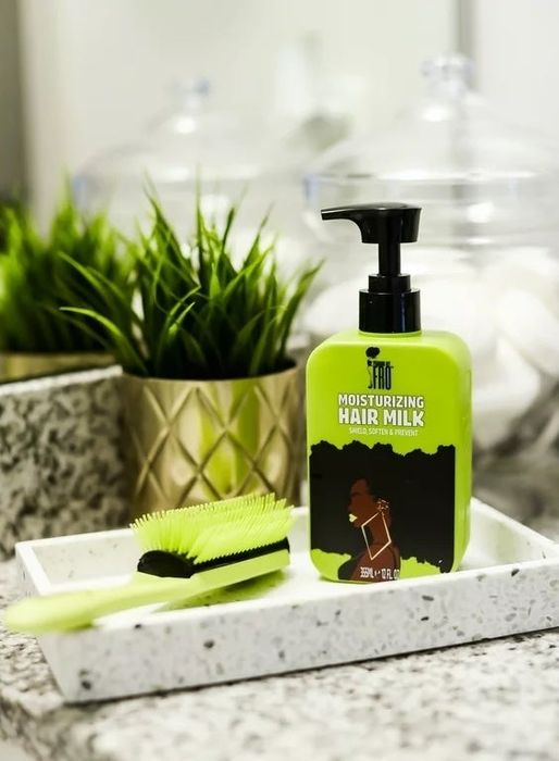 A green, black, and brown bottle of hair product with a green brush