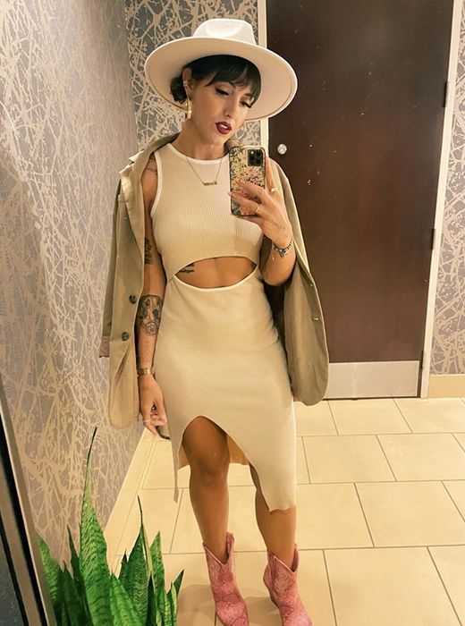 A person styling the dress in white, paired with bold pink boots.