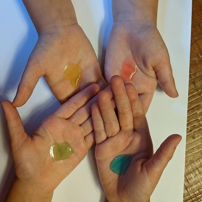 A reviewer's photo displaying blue, green, yellow, and red blobs of sanitizer applied to four hands