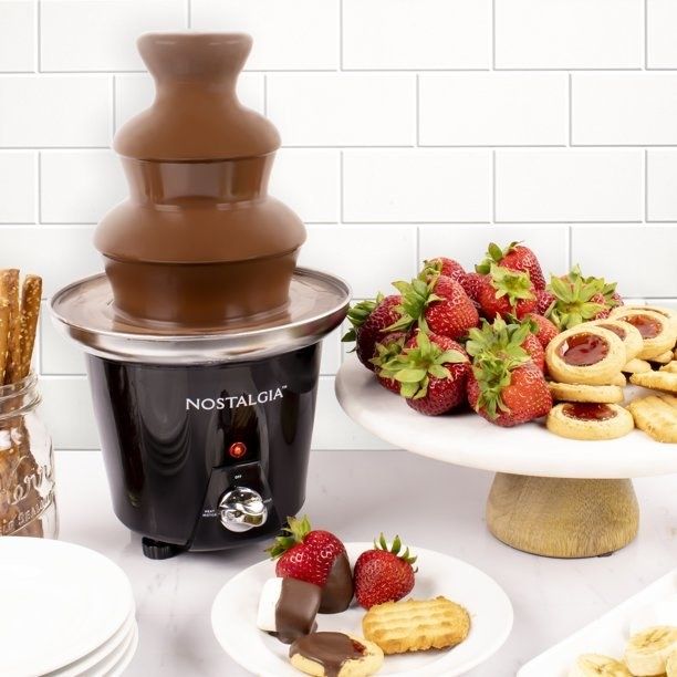 the chocolate fountain with fruit and various biscuits arranged next to it