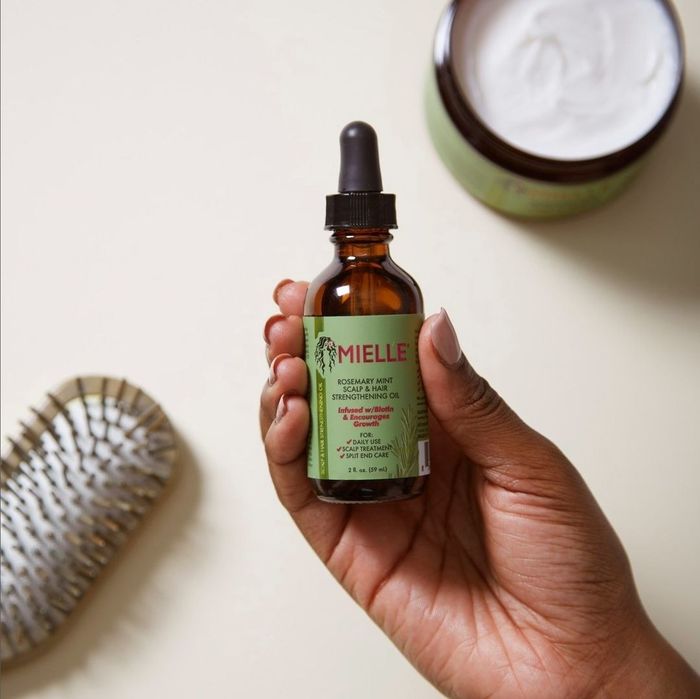 A hand grasping the hair oil