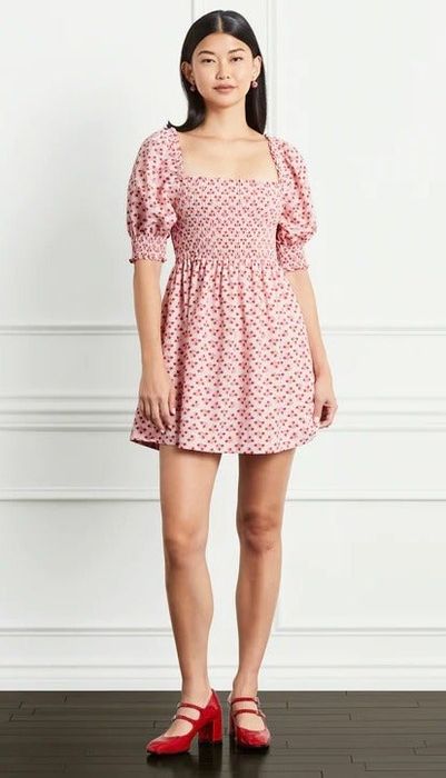 a model wearing the same dress in soft pink adorned with a red floral pattern