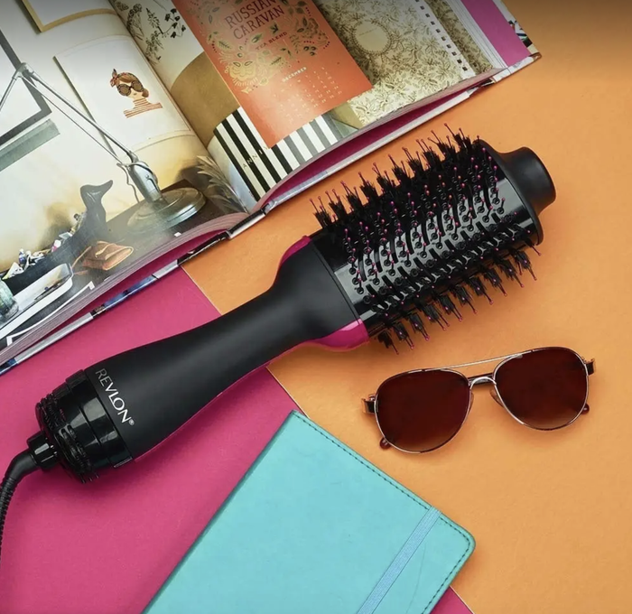 The dryer and volumizer, shaped like a round hairbrush with a cord extending from the end.