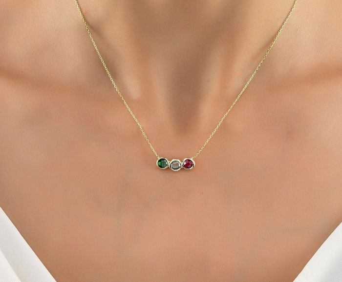 Close-up of a necklace featuring three gemstone accents set in hexagonal settings along a fine chain