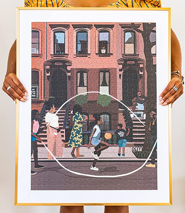 A person holding one of the finished puzzles framed.