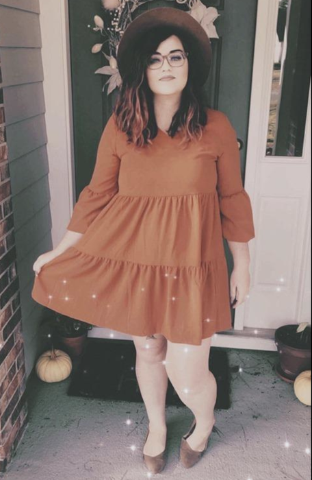 A reviewer in an orange tiered dress