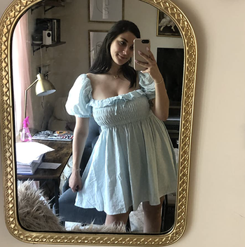 A reviewer in the blue version, standing to showcase the midi length