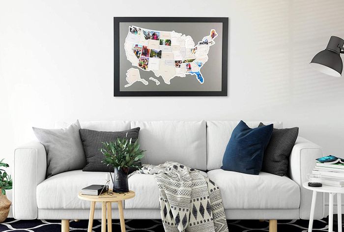 A framed map of the United States displayed in a living room with photos marking certain states you've visited together.