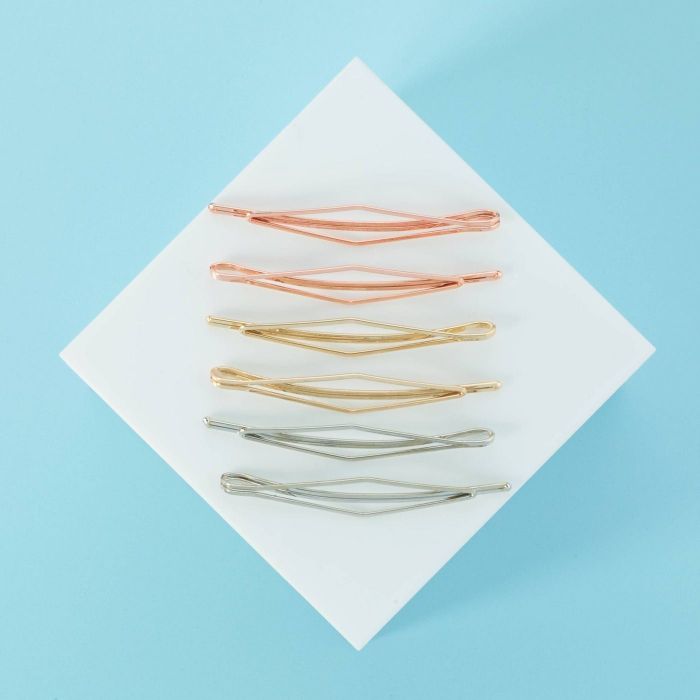 Rose gold, gold, and silver hair clips placed on a white and blue background