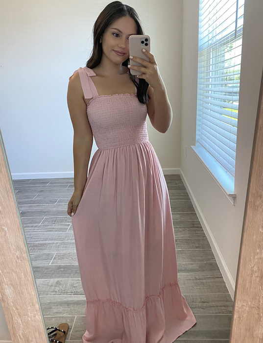 A reviewer wearing a light pink tiered maxi dress with tie sleeves