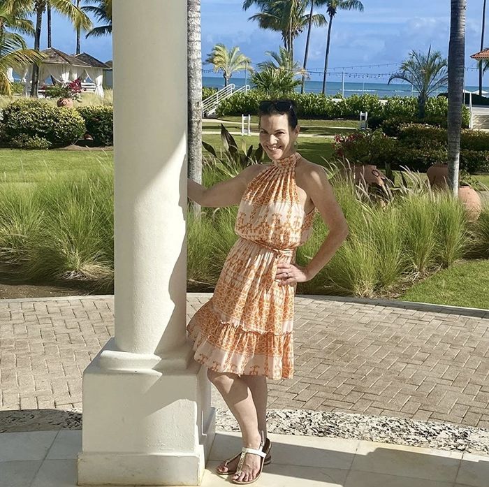 A reviewer wearing an orange patterned halterneck dress