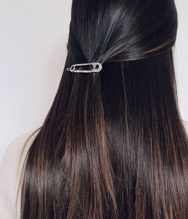 Model with brown hair wearing a silver safety pin