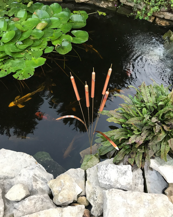 A full-size cattail wind chime placed in a koi pond.