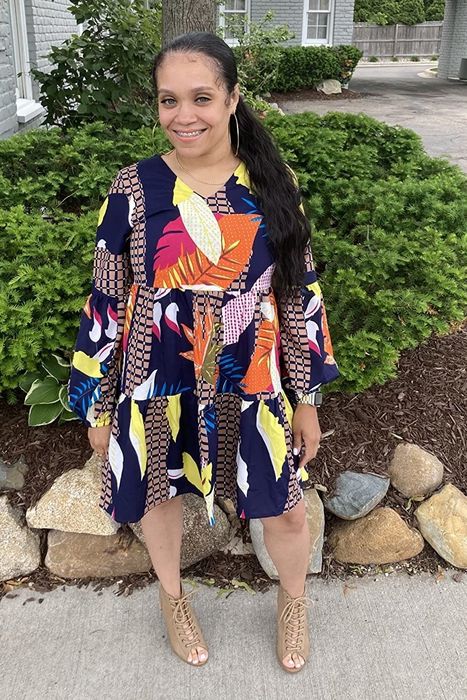a reviewer styled in the dress featuring a vibrant multicolored print, paired with lace-up heels