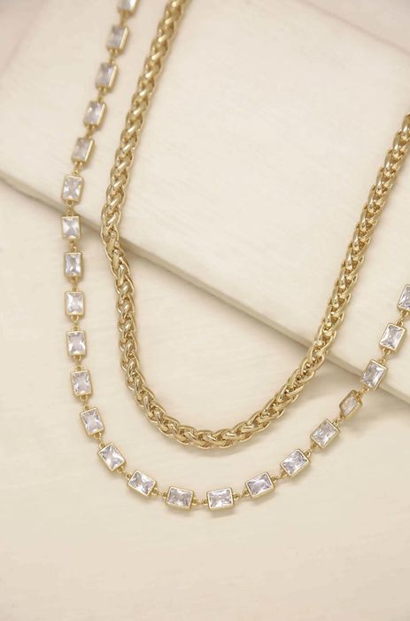 Gold chain necklace paired with a longer crystal square necklace.