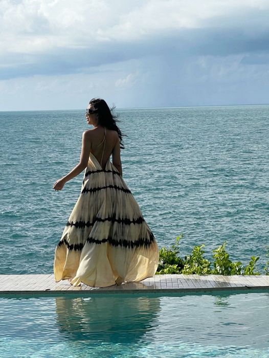 A model wearing a tie-dye white and black backless halter maxi dress