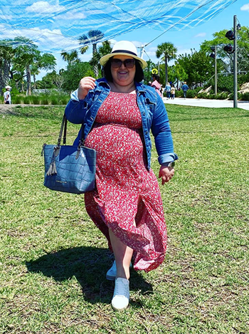 A reviewer in a red floral print dress paired with a denim jacket