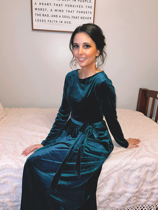 A reviewer wearing the dress in dark green.