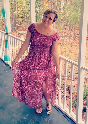 A reviewer wearing a red dress with the sleeves off the shoulder