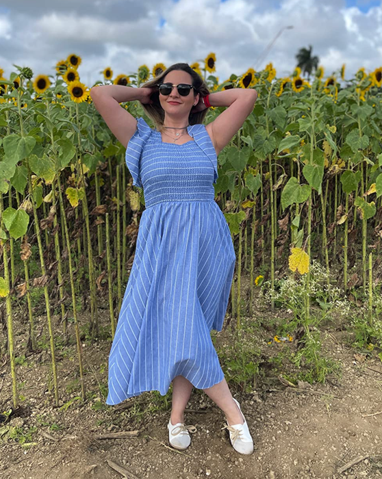 A reviewer in a blue smocked maxi dress with flutter sleeves