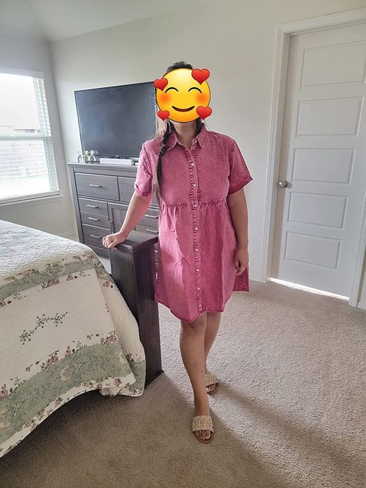 A reviewer sporting a pink denim mini dress, with a heart eyes emoji covering their face