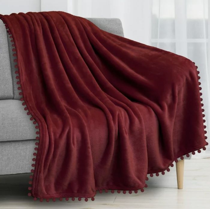 The rich crimson throw blanket casually draped over the couch, adding warmth to the room.