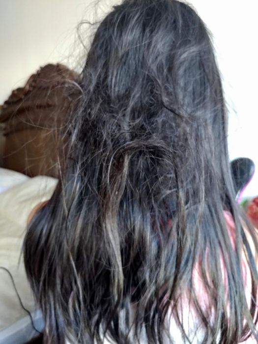 A reviewer's photo displaying tangled hair before using the detangler spray