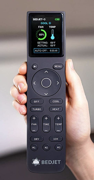 A hand holding the sleek black remote with a digital display screen