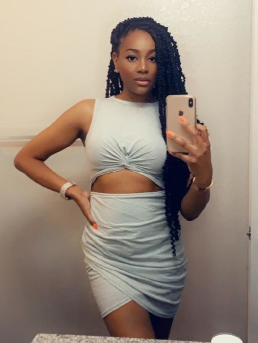 A reviewer wearing the grey midi dress with a high neckline and cutout detail just above the stomach