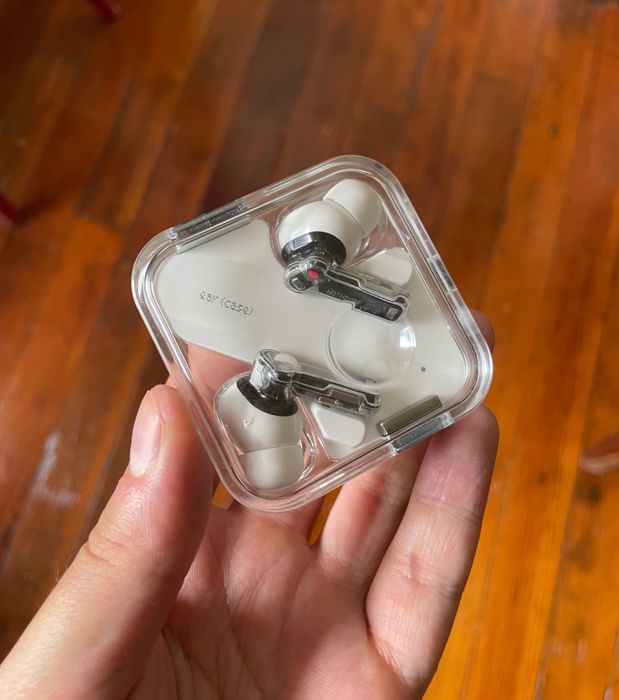 writer's white headphones resting in their transparent charging case