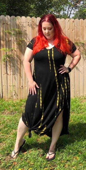 a reviewer rocking the short sleeve dress in black with yellow tie-dye accents and the hem tied in a knot