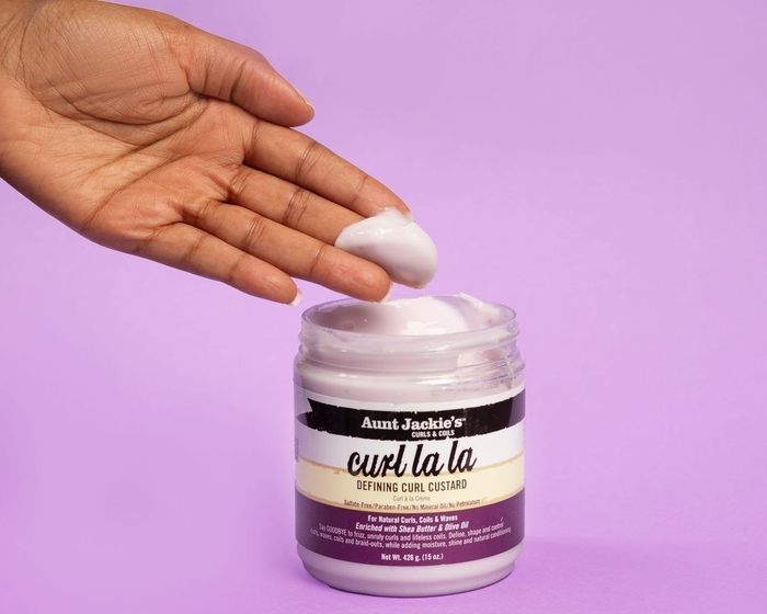 A hand scooping a generous dollop of the curl custard from the jar