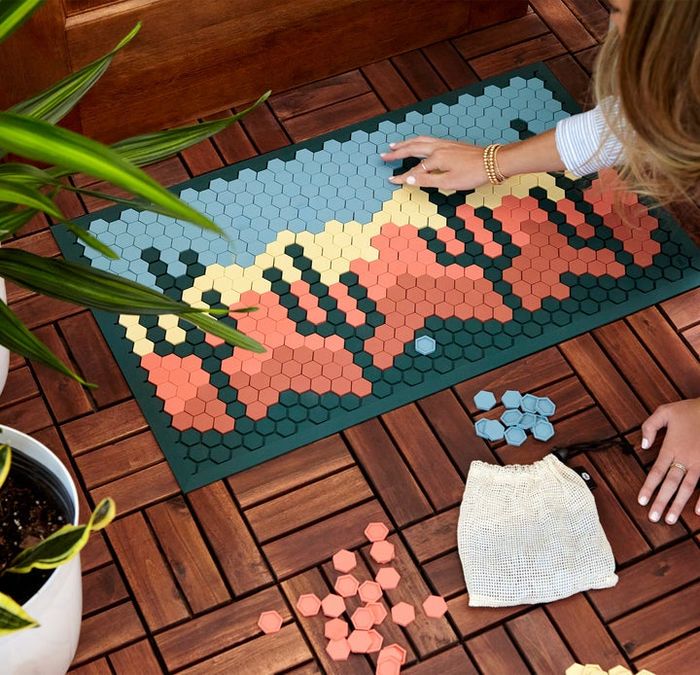A model crafting a desert landscape design on a tile mat.