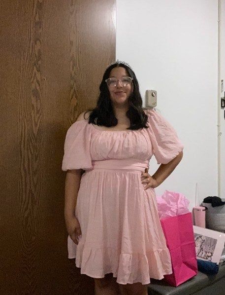 A reviewer is wearing the pink mini dress